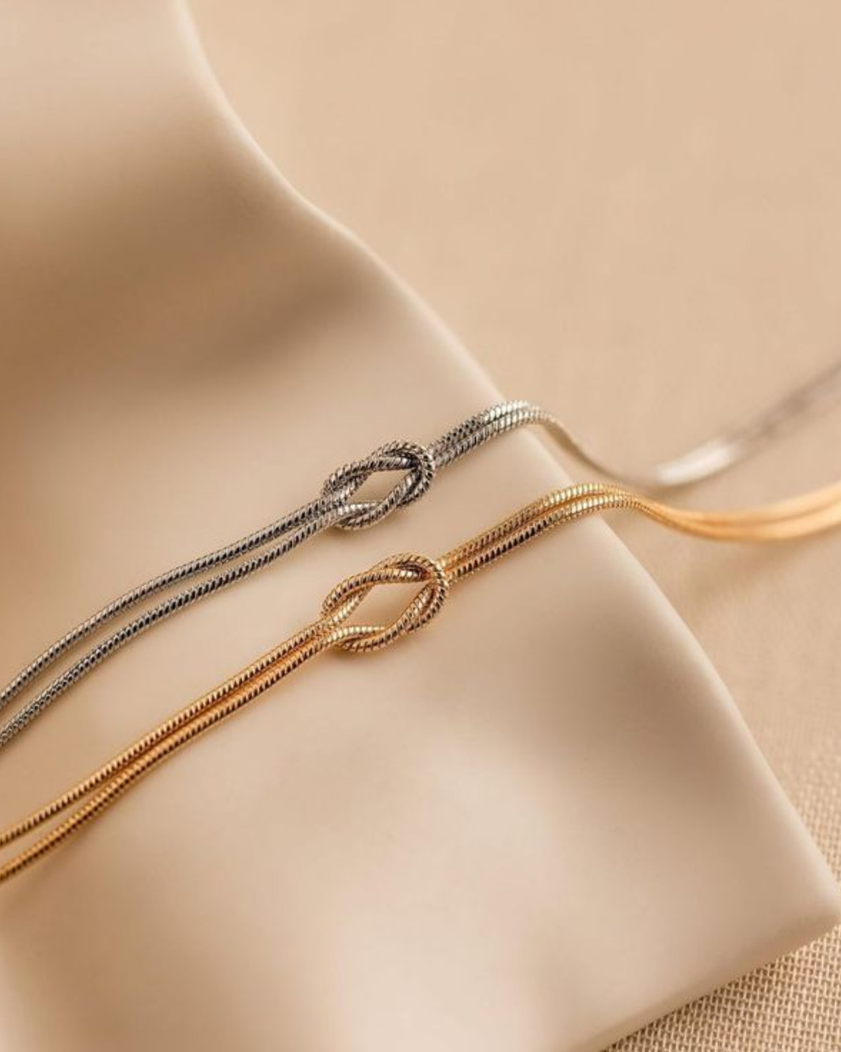 Close up of the love knot on silver and gold double snake chain bracelets