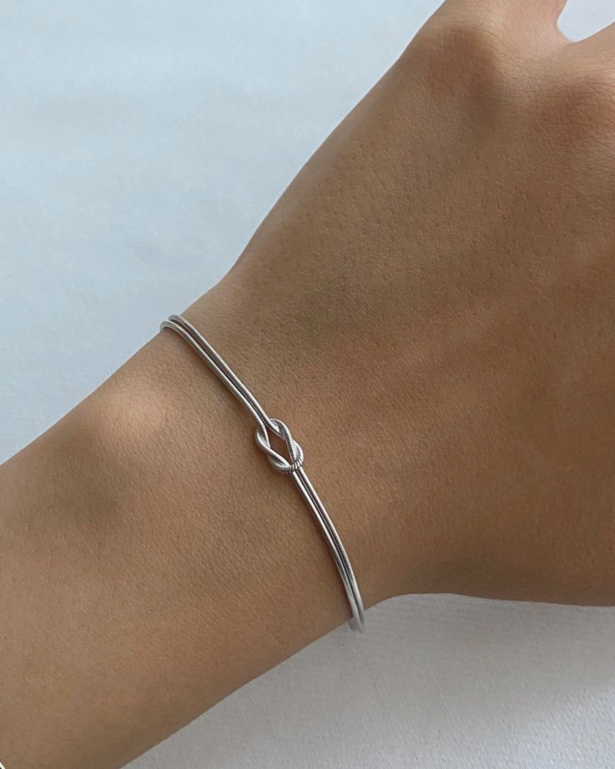 Silver love knot bracelet on a woman's wrist